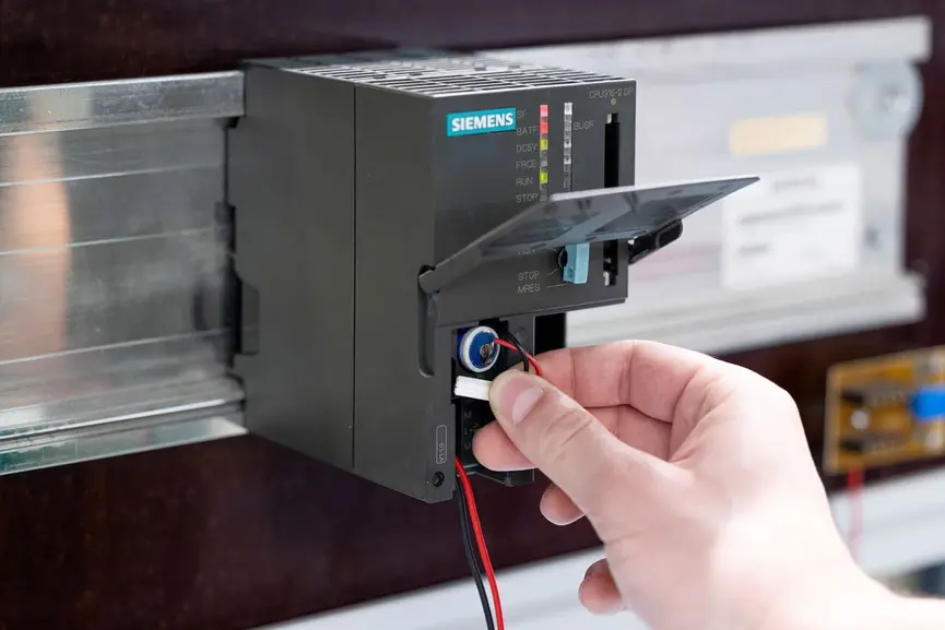 Schritt 4: Einsetzen der neuen Siemens SIMATIC S7-300 Pufferbatterie mit korrekter Polarität in das Batteriefach; bei verkabelter Ausführung zuerst Stecker mit CPU verbinden, dann Batterie einschieben und Abdeckung schließen. Der Wechsel sollte zügig erfolgen, um die interne Pufferung der CPU zu erhalten.