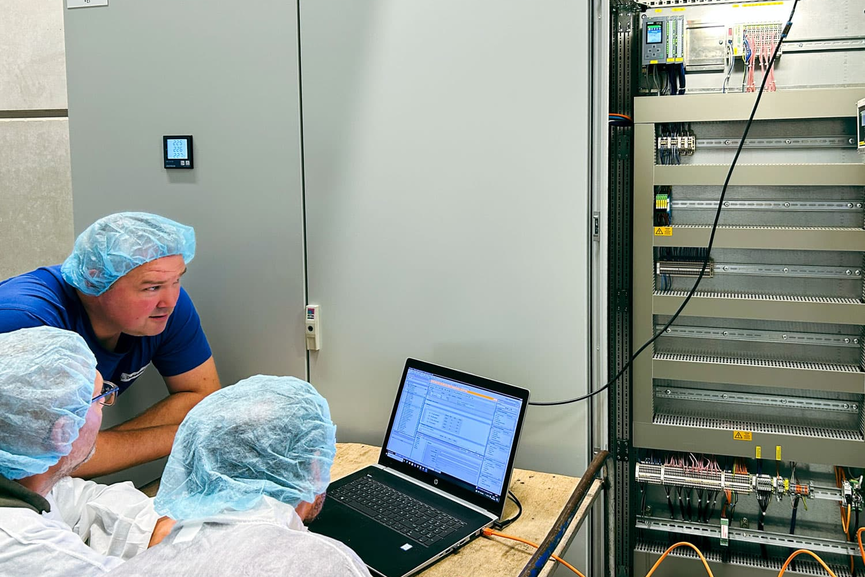 Instandhalter bei Zott prüfen einen Schaltschrank mit Siemens Simatic Programmiergerät