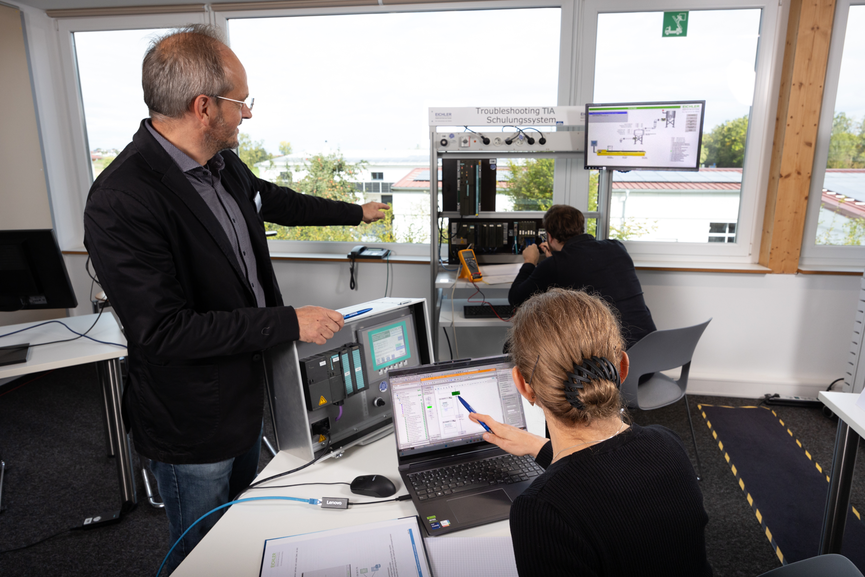 Schulungsleiter erklärt Teilnehmern das Fehlersuche-Simulationsrack auf einem Eichler Tia Portal Seminar